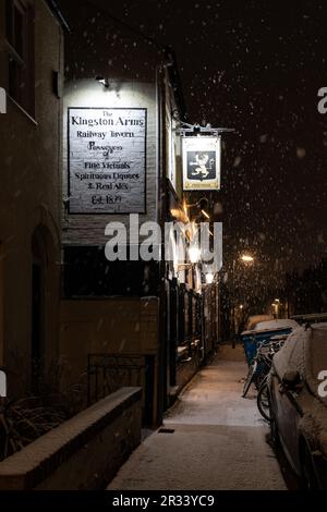 Le panneau pour le pub Kingston Arms brille lors d'une nuit d'hiver enneigée sur Kingston Street, à la sortie de Mill Road, Cambridge, Royaume-Uni Banque D'Images