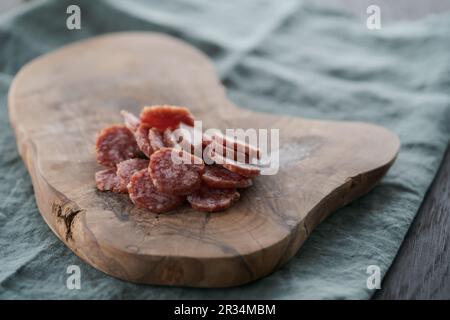 Saucisse séchée tranchée sur une planche de service d'olive, foyer peu profond Banque D'Images