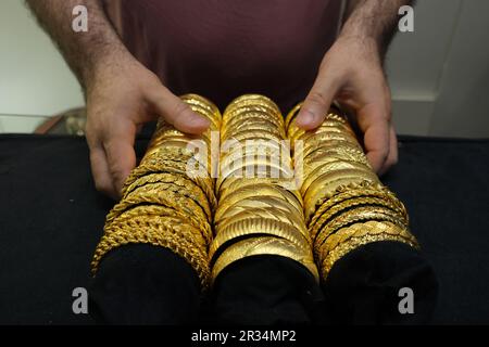 Bracelets or de luxe, trois rangées de bracelets or imitation sont dans la main de l'homme. Banque D'Images