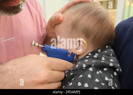 Petite fille ayant le processus de perçage d'oreille avec pistolet de perçage spécial dans le magasin de bijoux. Banque D'Images