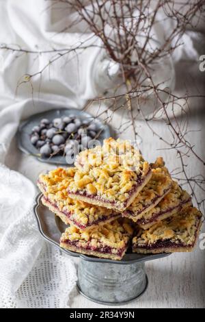 Tarte au streusel avec remplissage de cassis et de pétales de rose sur un fond clair. Banque D'Images