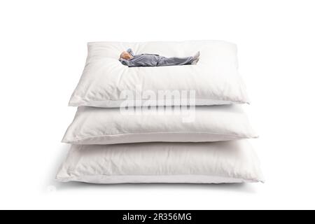 Homme mature en pyjama allongé sur un tas d'oreillers isolés sur fond blanc Banque D'Images