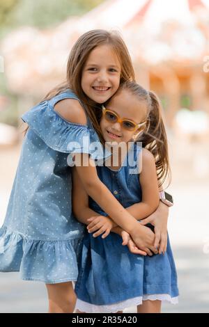 deux petites filles sont heureux de marcher dans le parc d'attractions en été. Journée internationale des enfants. Un enfant avec le syndrome de Down. Photo de haute qualité Banque D'Images