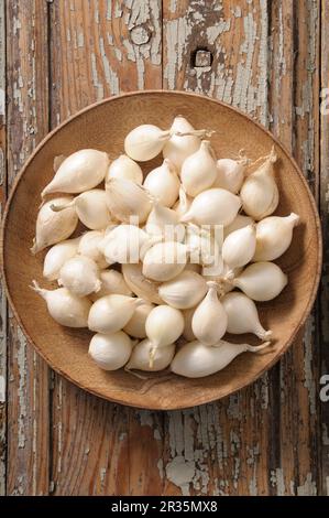 Petits oignons blancs sur une assiette en bois (vu d'en haut) Banque D'Images