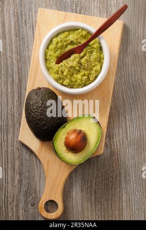 Guacamole et un avocat frais sur une planche à découper Banque D'Images