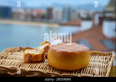 Fromage de vache fumé espagnol de Pria, Asturies, servi en plein air avec vue sur la plage de San Lorenzo et la promenade de Gijon Banque D'Images