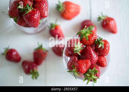 Fraîchement lavés les fraises dans les verres sur une surface en bois blanc Banque D'Images