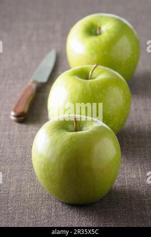 Trois pommes vertes sur nappe grise Banque D'Images