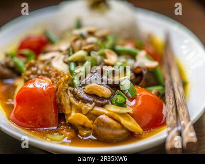 Poulet aux champignons, noix de cajou, tomates, haricots et un côté de riz (Asie) Banque D'Images