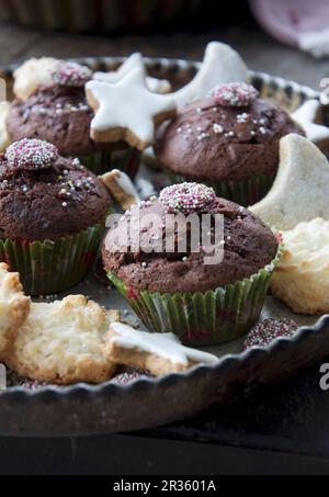 Un plateau de Noël avec des muffins au chocolat, des macarons à la noix de coco, des étoiles de cannelle et des biscuits au croissant de vanille Banque D'Images