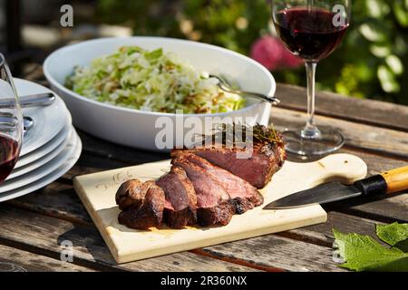 Bifteck avec une salade de chou sur une table de jardin Banque D'Images