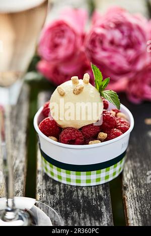 Crème glacée au caramel et à la vanille avec framboises fraîches sur une table de jardin Banque D'Images
