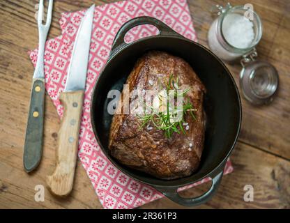 Rôtir le bœuf avec du romarin et de l'ail dans une casserole Banque D'Images