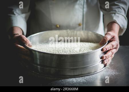 Un pâtissier avec un grand tamis de sucre glace Banque D'Images