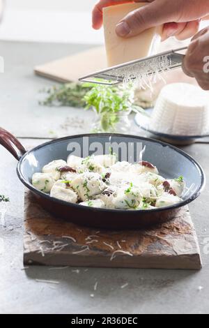 Le parmesan est râpé sur des gnocchi avec de la ricotta et des herbes Banque D'Images