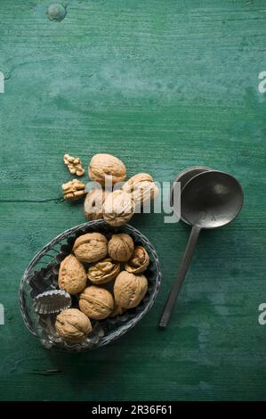 Noix, décortiquées et non décortiquées, dans un bol sur une surface en bois rustique à côté d'une cuillère Banque D'Images