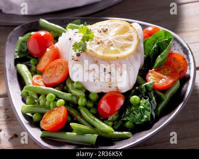 Filet de morue sur un lit de légumes Banque D'Images