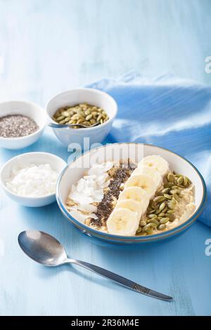 Porridge aux bananes, graines de citrouille, graines de chia et flocons de noix de coco Banque D'Images