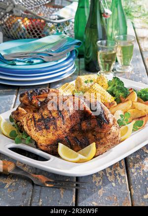Demi-poulet rôti à l'ail grillé avec des quartiers de maïs et de pommes de terre Banque D'Images