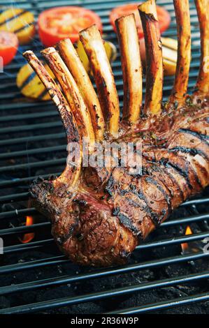 Un carré d'agneau aux herbes et du vin sur un gril Banque D'Images