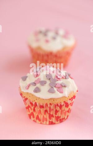 Petits gâteaux nappés de crème et décorés de coeurs de sucre Banque D'Images