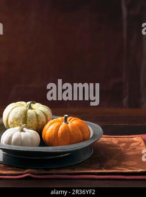 Un arrangement de trois citrouilles décoratives dans un plat en métal gris Banque D'Images