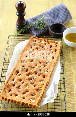 Focaccia végétalienne avec tomates séchées, ail et herbes sur une grille de refroidissement Banque D'Images