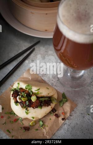 Pain de Bao cuit à la vapeur vegan rempli de tofu fumé et de châtaignes marinées au soja, huile de sésame, sauce Chili et ail, recouvert de rondelles de printemps Banque D'Images