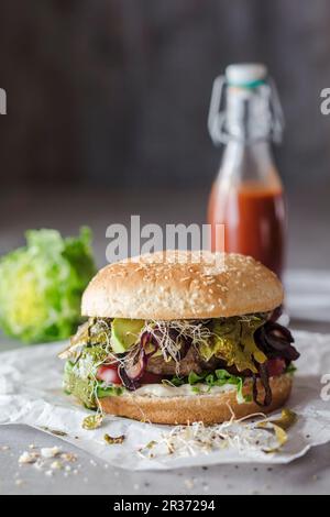 Un hamburger avec du bacon aux algues, des pousses de haricots et du ketchup aux fraises Banque D'Images