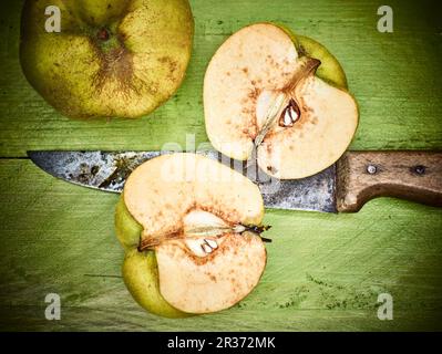 Quinces, entières et coupées en deux, avec un couteau rouillé Banque D'Images