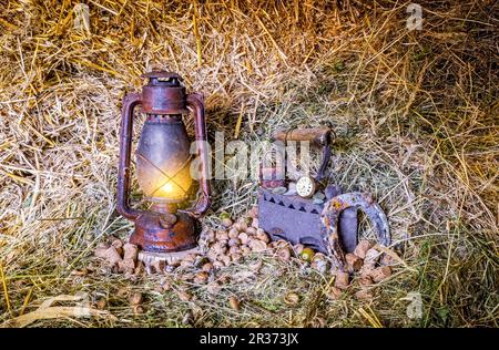 Lampe lanterne rouge vintage à l'huile de kérosène allumée et vieilles choses dans le foin Banque D'Images