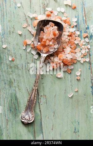 Cuillère d'argent Vinatge remplie de sel de mer rose de l'Himalaya sur une surface rustique en bois bleu vert Banque D'Images