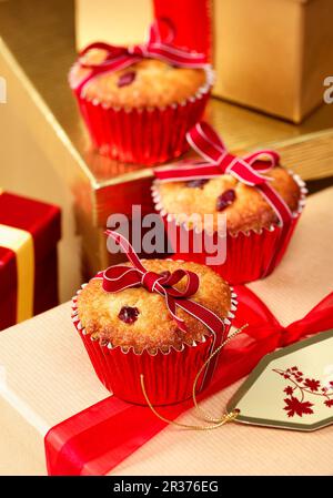 Trois muffins aux canneberges et à la massepain de fête, attachés avec un ruban, assis sur des cadeaux emballés dans un cadre de Noël Banque D'Images