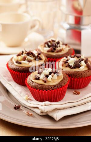 Petits gâteaux de marrons moka sur une serviette crème et une assiette avec tasses à café et percolateur en arrière-plan Banque D'Images