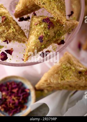 Baklava pistache aux pétales de rose sur un support à gâteau avec une serviette rose Banque D'Images