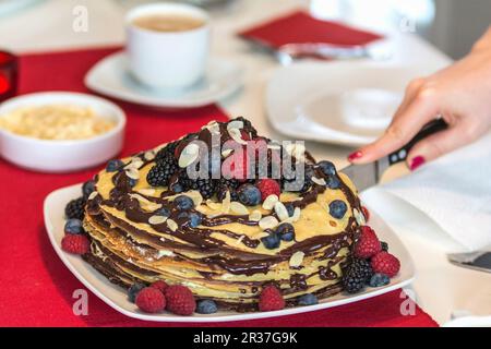 Un gâteau à la crêpe avec des baies et de la sauce au chocolat en tranches Banque D'Images