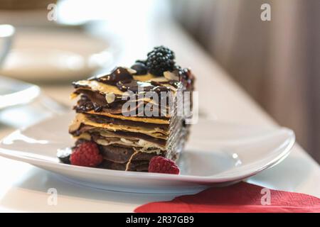 Une tranche de gâteau de crêpes aux fruits rouges et sauce au chocolat Banque D'Images