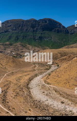 Rivière sèche avant les falaises de roche verte, Salalah, Oman Banque D'Images