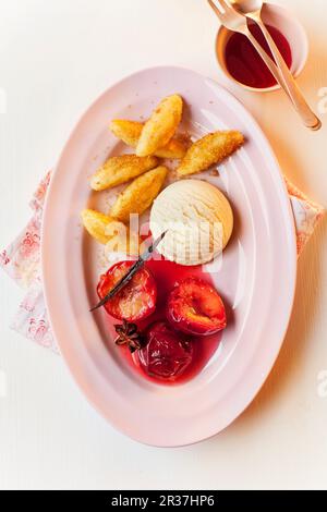 'Chupfnudeln' (boulettes de pommes de terre en forme de doigt) avec de la crème glacée à la vanille et des prunes imbibées de Porto Banque D'Images