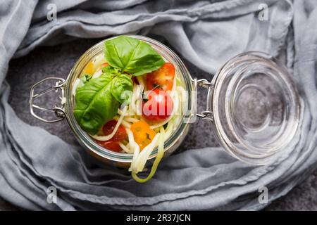 Zoodles (courgettes nouilles) dans un bocal en verre avec tomates et basilic Banque D'Images