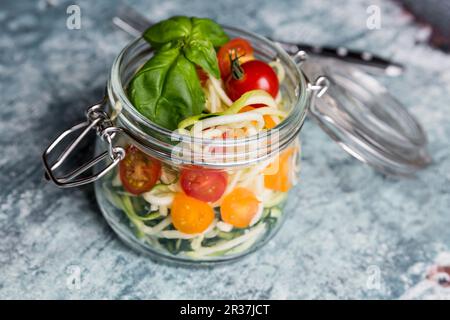 Zoodles (courgettes nouilles) dans un bocal en verre avec tomates et basilic Banque D'Images