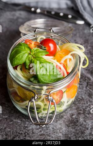 Zoodles (courgettes nouilles) dans un bocal en verre avec tomates et basilic Banque D'Images