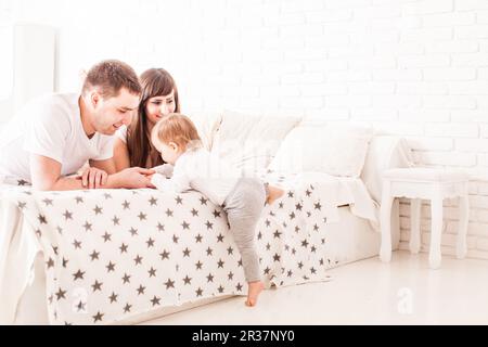 Les parents à enseigner à l'enfant de grimper sur le lit Banque D'Images