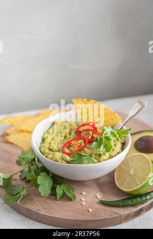 Guacamole d'avocat dans un bol avec coriandre et piment Banque D'Images