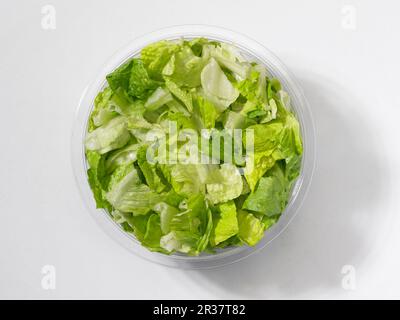 Feuilles de laitue verte fraîche dans un bol en plastique devant un fond blanc (vu d'en haut) Banque D'Images