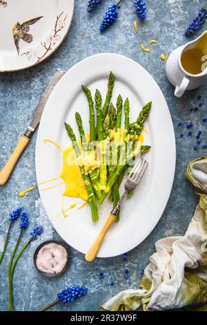 Asperges vertes avec sauce hollandaise sur une assiette de service (vue de dessus) Banque D'Images