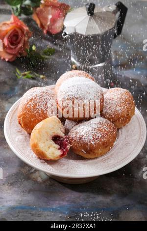 Le sucre glace étant tamisé sur une assiette de beignets de confiture Banque D'Images