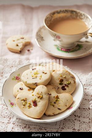 Biscuits avec pistaches et pétales de rose séchés, servis avec une tasse de café Banque D'Images