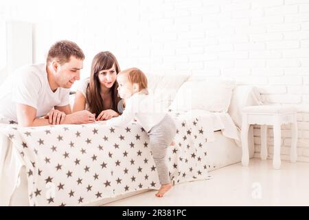 Les parents à enseigner à l'enfant de grimper sur le lit Banque D'Images