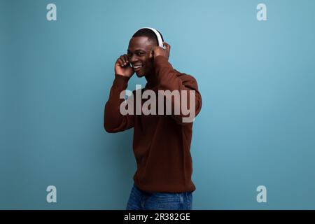 un homme américain à la peau sombre et énergique avec un casque sans fil moderne à l'arrière-plan et un espace de copie Banque D'Images